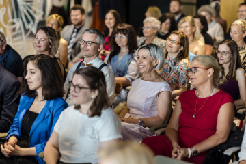 Pozorní a usmívající se účastníci sedí v publiku a sledují probíhající program